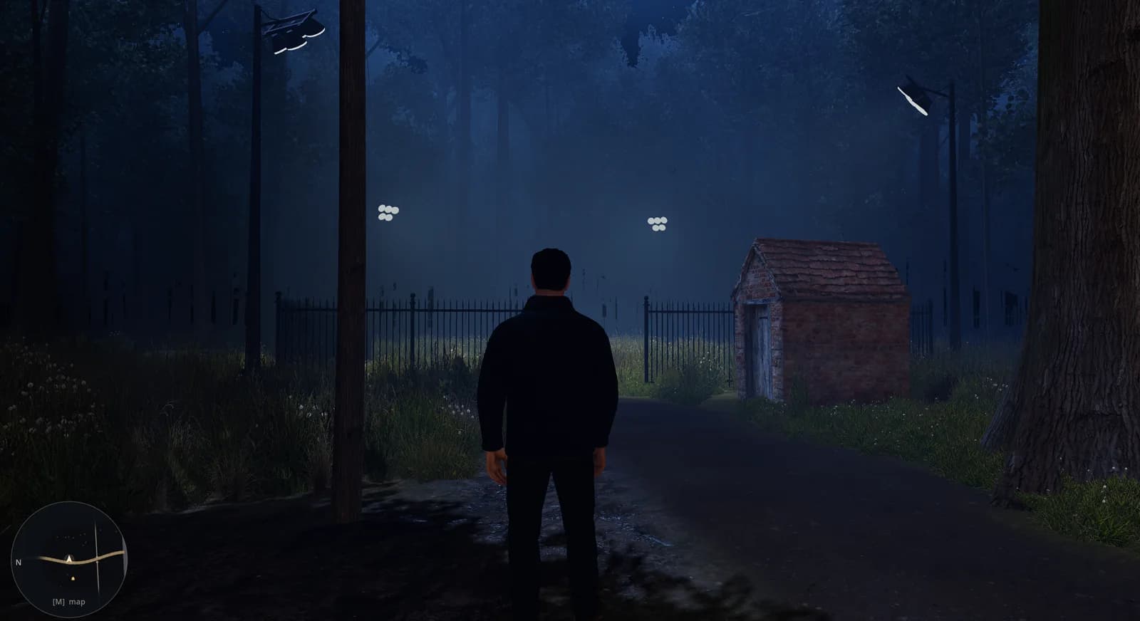 Standing at the fence line at night, the brick shed lit beyond the gate
